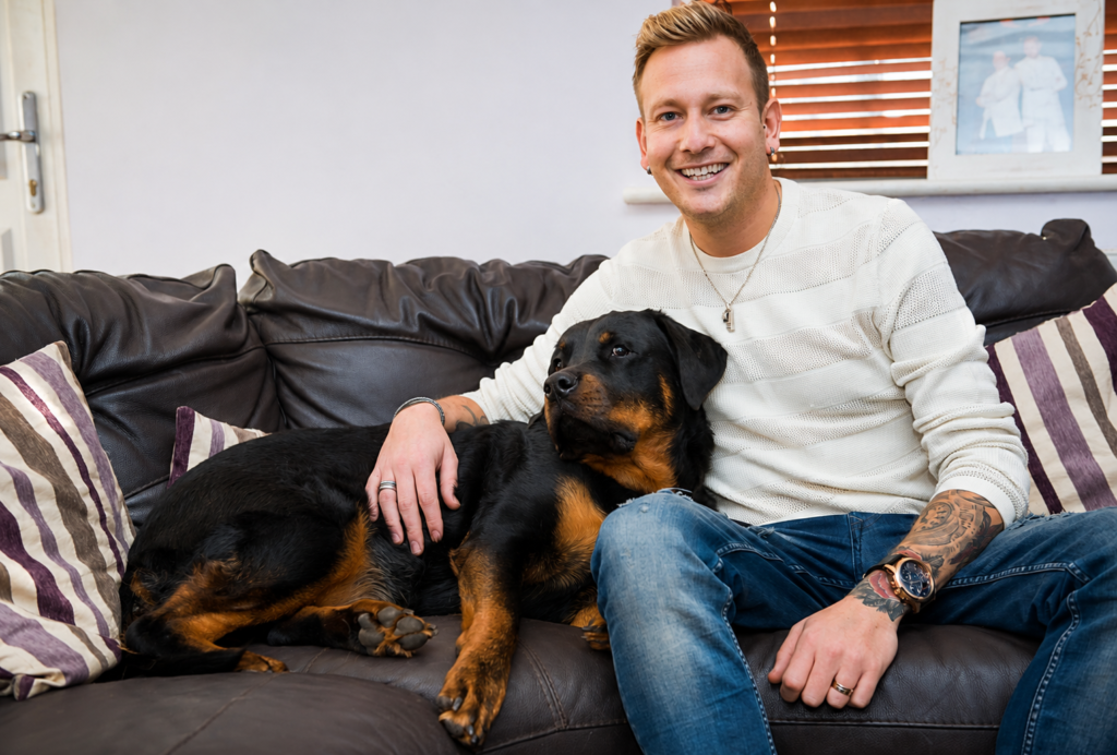 Rottweiler acostado en el sofá junto a su dueño mostrando su temperamento tranquilo en casa